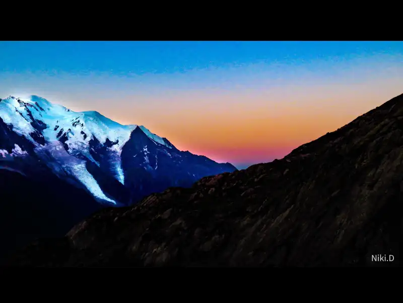 Lever de soleil sur le Mont-Blanc, l'orange et le bleu du ciel contrastent avec les neiges éternelles de la montagne.